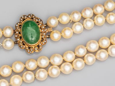 un gros plan sur un collier composé de perles et d'une pierre verte
