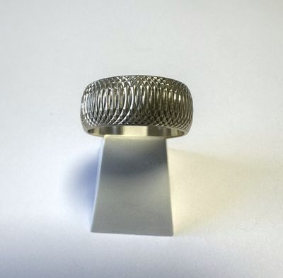 un gros plan d'une bague en argent posée sur un support, sur une surface blanche