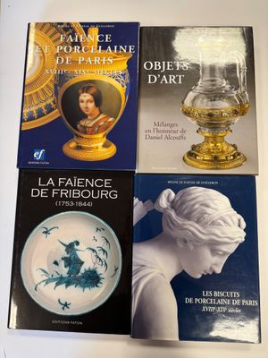 quatre livres posés sur une table, avec un vase posé dessus