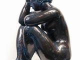 statue of a man sitting on a pedestal with his head in his hands