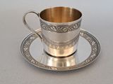 a silver cup and saucer sitting on a saucer