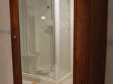une armoire en bois avec une porte vitrée dans une salle de bains
