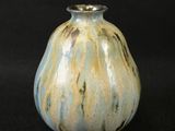 a blue and yellow vase sitting on a black surface