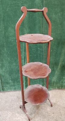 a three tiered wooden stand with a green curtain in the background