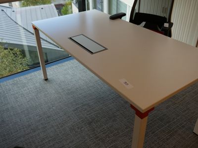 une table blanche sur laquelle est posé un téléphone portable, devant une fenêtre