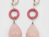 une paire de boucles d'oreilles roses et dorées sur fond blanc