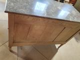 a wooden cabinet with a marble top on a tile floor