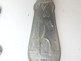 a silver spoon hanging on a wall next to a white wall