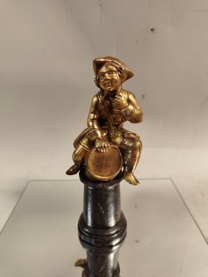 brass figurine of a boy sitting on top of a pipe