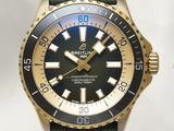une montre dorée et noire avec un bracelet vert