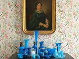 un tableau accroché au mur au-dessus d'une commode sur laquelle sont posés des vases bleus