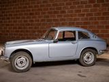 a small blue car that is parked in front of a brick wall