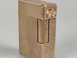 an antique gold cigarette case with a cigarette lighter in the background