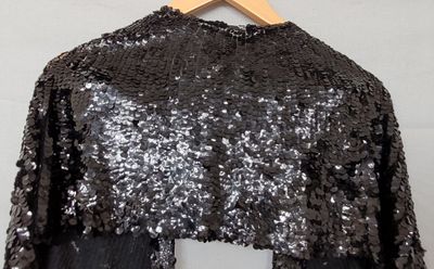 un haut à paillettes noires et argentées suspendu à un cintre en bois
