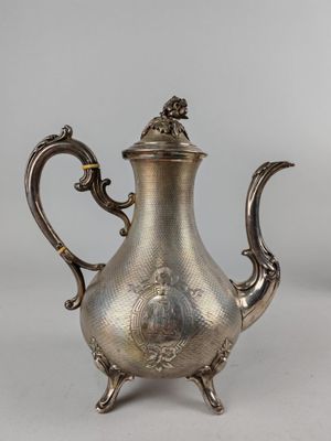 a silver tea pot with a handle and a handle on a stand
