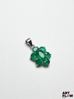 un gros plan d'un pendentif vert posé sur une surface blanche