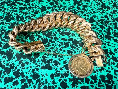 a close up of a gold bracelet with a coin on a green and black background