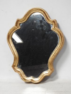 une image représentant un miroir à cadre doré posé sur un mur blanc
