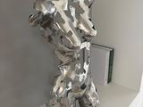 une sculpture en argent représentant un chien, posée sur une étagère