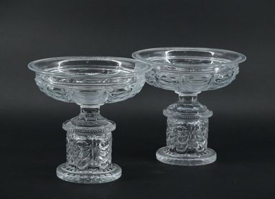 pair of clear glass footed bowls on pedestals against a black background