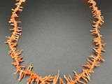a necklace made of orange coral coral beads on a black surface