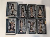 six bronze figurines of women in boxes on a white surface