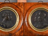 pair of antique bronze portraits of a man and woman on a wooden plaque