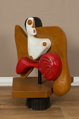 une sculpture représentant une femme assise sur une chaise, un cœur rouge sur les genoux