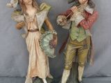 deux figurines représentant un homme et une femme portant un chapeau et une queue-de-pie