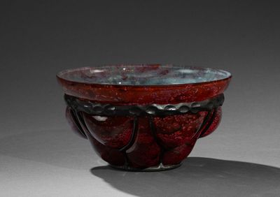 un bol rouge posé sur une table, dont l'ombre se projette sur le sol