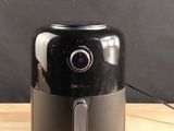 a black and silver air fryer sitting on a wooden table
