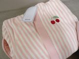 a pink and white striped blanket with a cherry on it