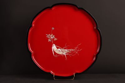 une assiette rouge décorée d'un oiseau et de fleurs