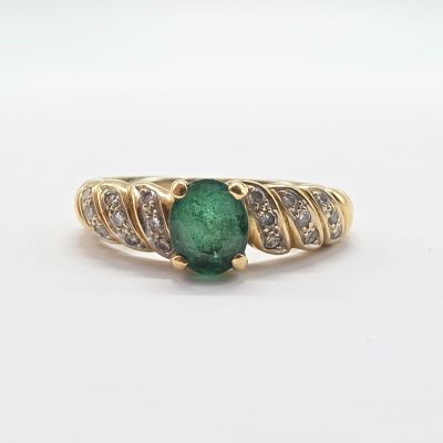 une image d'une bague avec une pierre verte entourée de diamants