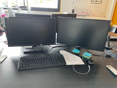 deux écrans d'ordinateur posés sur un bureau avec un clavier et une souris