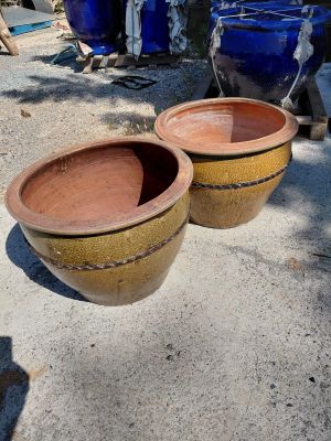 two large brown pots sitting on the ground