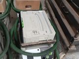 une pile d'équipements électroniques posée sur le sol à côté d'une pile de cartons