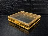 une boîte en or contenant un miroir sur une surface noire