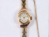a gold wrist watch with a chain on a white surface