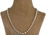 un gros plan d'un mannequin portant un collier de perles blanches