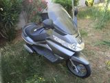 a scooter that is parked in the grass by the bushes