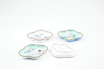 four porcelain dishes with flowers and leaves on them on a white surface