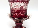 a red glass vase with a floral design on it
