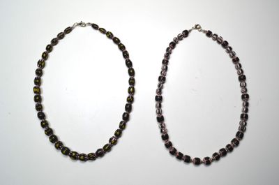 deux colliers composés de perles vertes et noires sur un fond blanc