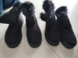trois paires de bottes noires sont alignées sur le sol