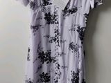 une robe à fleurs violette et noire suspendue à un cintre devant un mur blanc