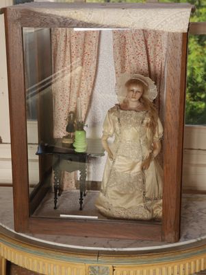 une poupée dans une vitrine posée sur une table