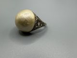 un gros plan d'une bague ornée d'une perle posée sur une table