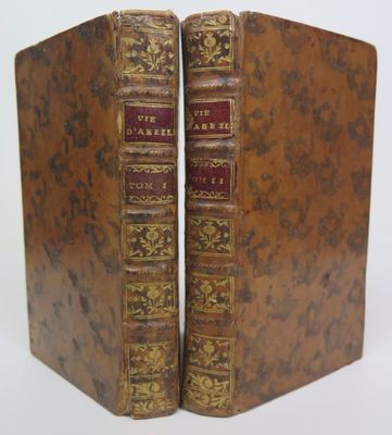 two old books sitting on top of each other on a white surface