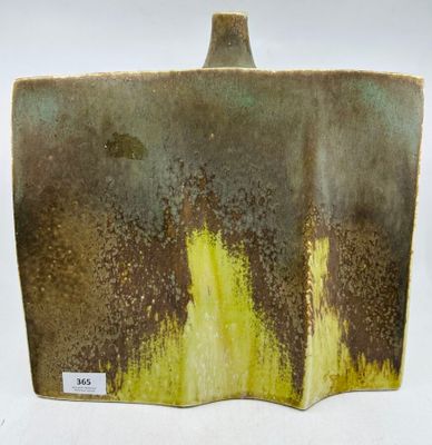 un vase marron et jaune posé sur une surface blanche